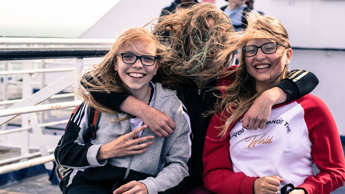 배 갑판에 있는 세 소녀가 카메라를 비웃는다.